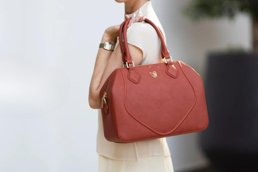 a woman carrying a red handbag while walking down a street